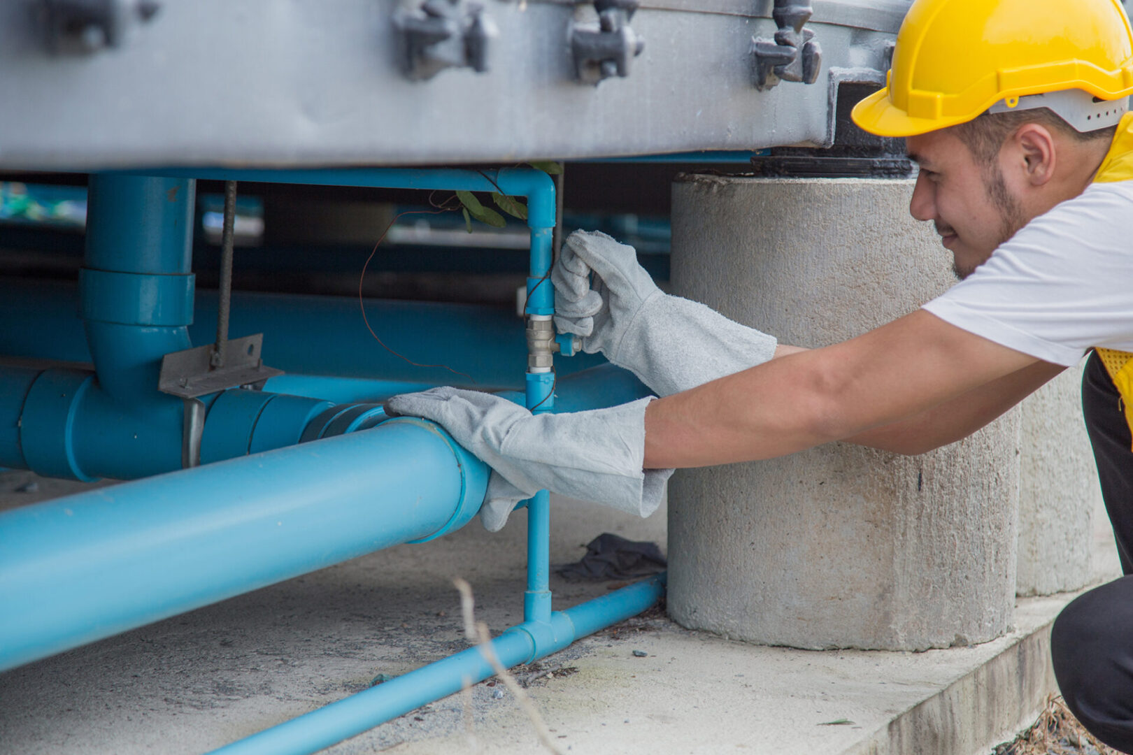 The worker wearing the yellow hard safety hat was repairing the water pipe line under the building with service mind.